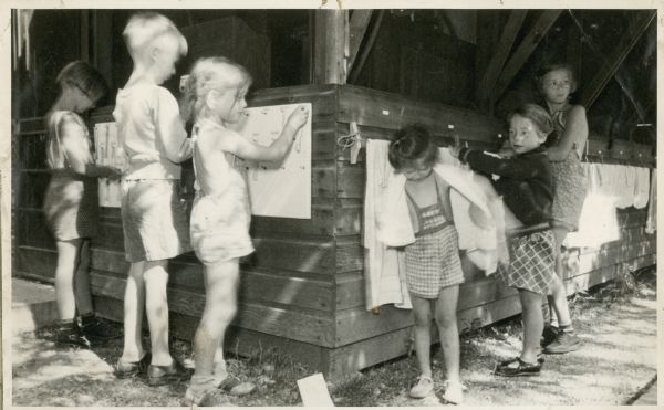 Children at camp hang up their towels outdoors.