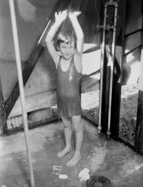 Young girl in bathing suit standing under the shower at "The Capital Times" Kiddie Camp.