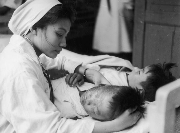 Nurse caring for two North Vietnamese children who were wounded by U.S. bombing. This official North Vietnamese photograph was released about June 1, 1966, and received by the National Coordinating Committee Against the War in Vietnam in Madison for publication in its newsletter.