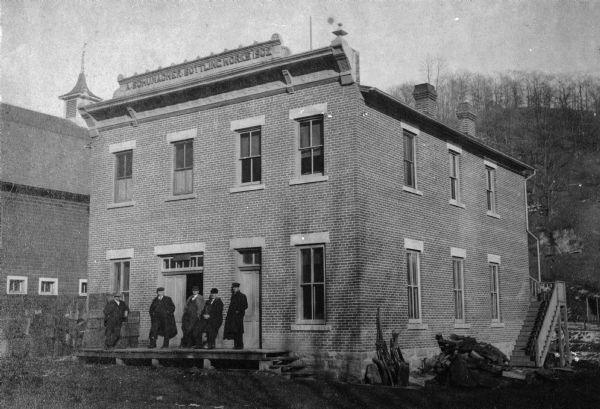Exterior view of the bottling works of the Potosi Brewery built in 1902. A group of men stand near the front entrance.