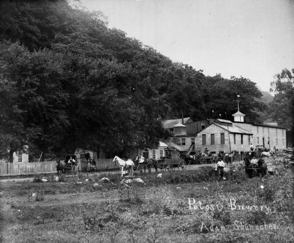 Exterior view of the Potosi Brewery at about the time Adam Schumacher took over the operation. Children and adults can be seen near a fence and in horse-drawn vehicles and riding horses near the brewery.