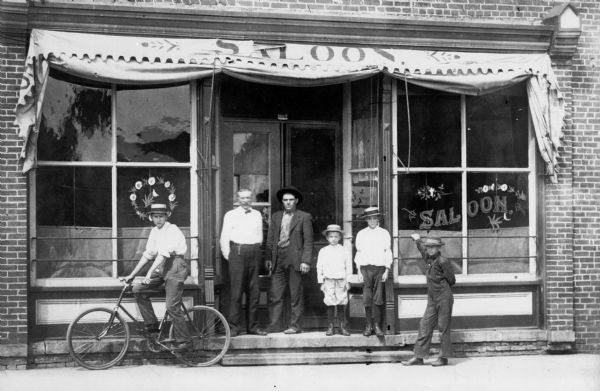 Exterior view of the Stevens Point saloon owned by Albert Liss, a German immigrant.  The saloon was located in the Polish North Ward known as the "Devil's Elbow".  A group, including four young boys with one on a bicycle, are standing in front of the bar.