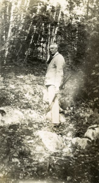 Frederick Jackson Turner poses with a gun in his hand outdoors at Hancock Point on Frenchman's Bay.