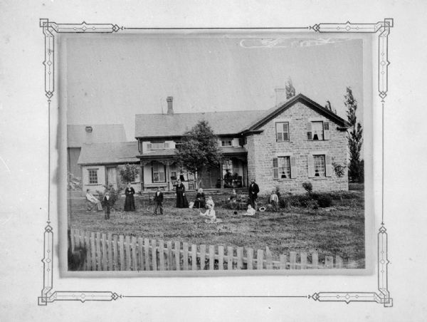 The Hatleberg family playing croquet in front of their stone upright and wing house, two miles east of DeForest near the present day intersection of Mueller Road and County Trunk C.