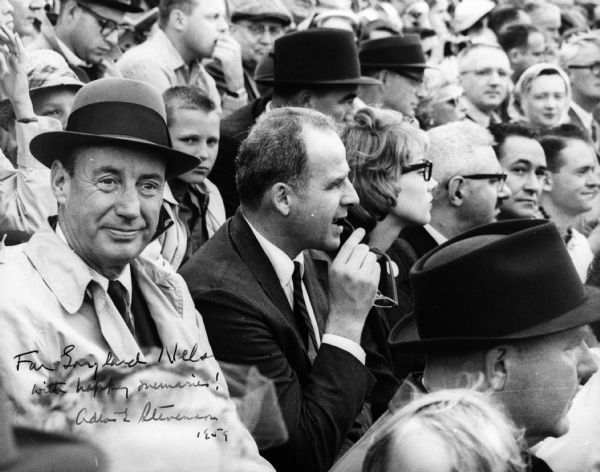 Adlai Stevenson and Governor Gaylord Nelson seated together at an unidentified event, probably a sporting event.