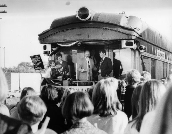 During his campaign for re-election to the Senate, Senator Gaylord Nelson revived an old campaign tradition by campaigning from the back of a train.  At this stop Nelson's wife and children have joined him at the rear of the train.
