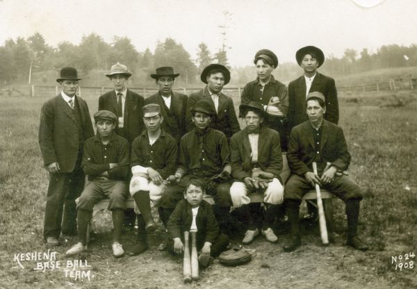Group portrait of the Kenshena Baseball team with a bat boy in the foreground.
