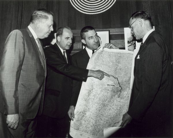 Gaylord Nelson points to a map of the Wolf River, as John Race, Stewart Udall, and Henry Reuss look on.