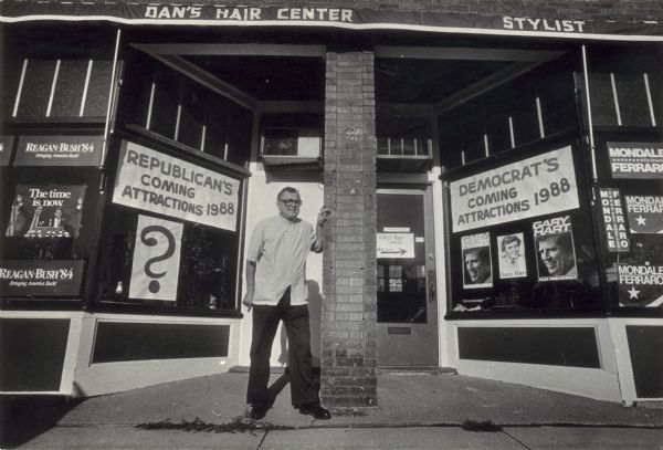 Barber Guy Marty poses in front of Dan's Hair Center, which has both Democrat and Republican posters in the windows.