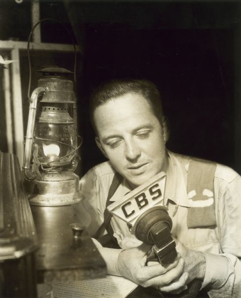 War reporter John Charles Daly gives his radio report by the light of a kerosene lantern.
