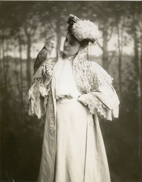Studio portrait of Lenore Harrison Cawker holding a parrot on her hand.