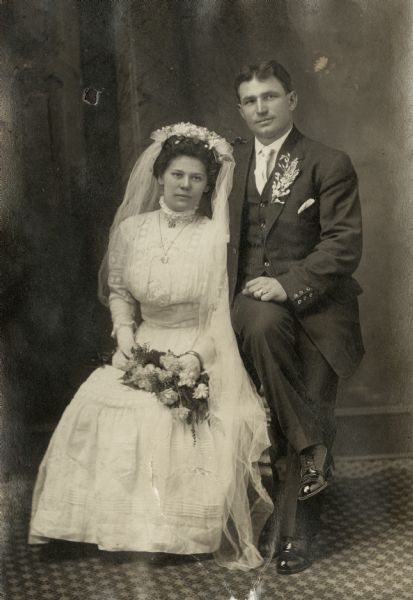 Studio portrait of Rose and Louis Meyer. Rose Swetlik (1892-1968) married Louis Meyer (1887-1949), a farmer, on February 28, 1911 in Kossuth Township (Manitowoc Co.), WI. The wedding party then drove to Manitowoc to have their photographs taken. Bride and groom are seated and wearing formal wedding attire.