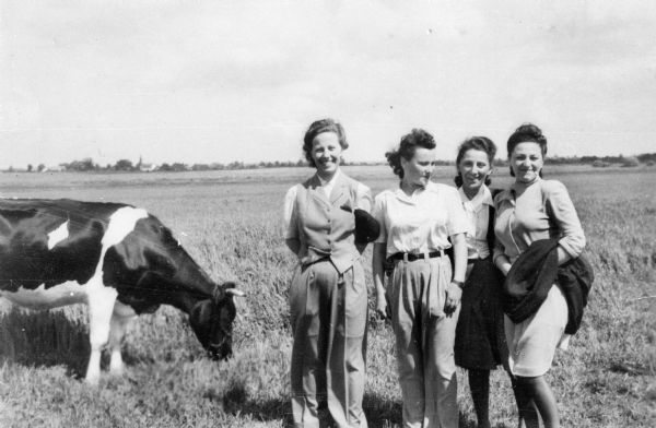 Pela Rosen Alpert and friends stand in a field next to a cow. From left: Mrs. Schain, Pela Rosen Alpert, unidentified friend, Celinda Lippman; Sweden.