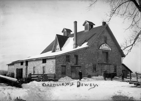 Exterior of barn built by Nelson Dewey at Cassville, seen in about 1905 when the property was owned by T.J. Bunn.  The building is now the State Farm Museum, part of the Historical Society's Stonefield Historic Site.