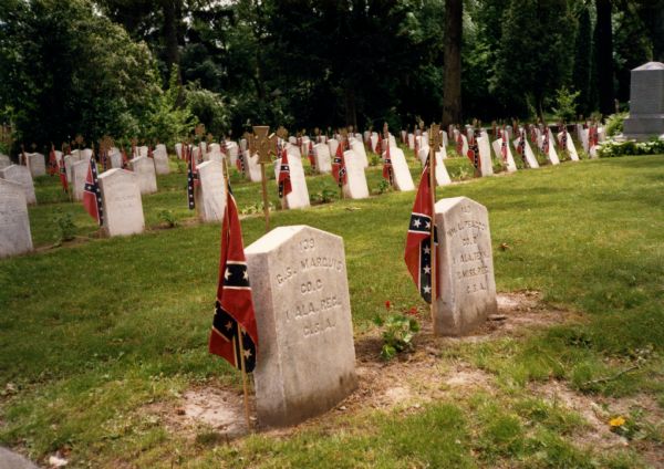 Confederate Graves at Forest Hill Cemetery. Each headstone has a Confederate flag stuck in the earth next to it.