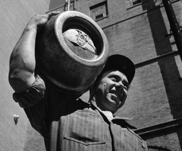 Miller delivery man carrying a keg of Miller Beer on his shoulder.