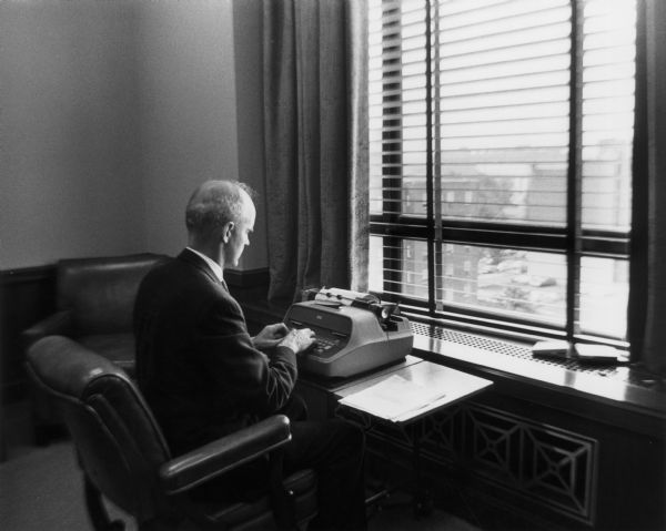 Senator William Proxmire seated in an office using a typewriter.