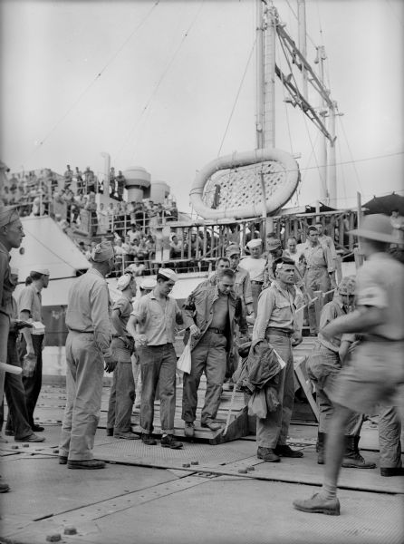 Wounded soldiers are led from the USS <i>Samaritan</i>, a hospital ship.