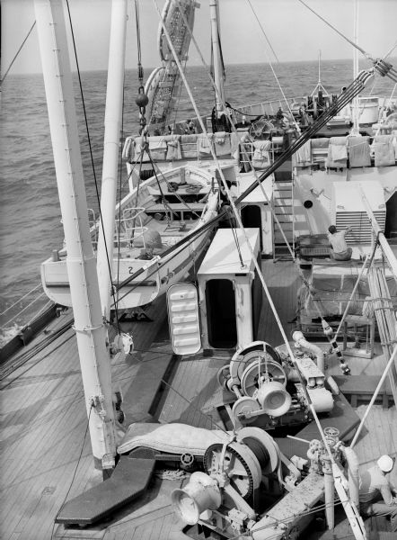 Deck of the hospital ship USS <i>Samaritan</i> at sea. There are various forms of bedding and mattresses airing out on the railings and on the deck.