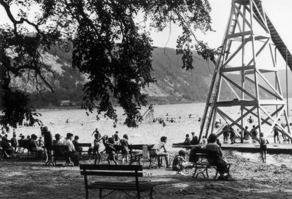 Children and adults gather at Devil's Lake. Shown at the right is a  large water slide.