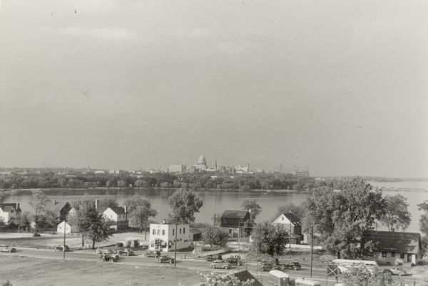 Elevated view of 900 block South Park Street, with Lake Monona and the Wisconsin State Capitol in the background.  The two-story white building in the foreground is 927 South Park Street (Carl Felly's Iron Lantern Restaurant from 1935 - 1957) and two of the houses to the right on West Shore Drive are 928 West Shore Drive and 934 West Shore Drive.