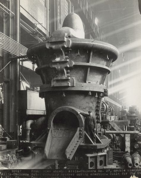 View inside the Allis-Chalmers plant of #27 double discharge Gates Gyratory Breaker during erection. It was built for the Utah Copper Company. There is a man in work clothes and hat standing on the right.