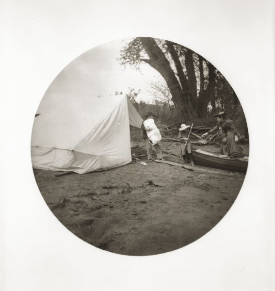 Setting up camp on a bank of the Youghiogheny River. William Turville holds a canvas bag of bedding, while Jessie hands her son Fredrik a satchel from the boat.