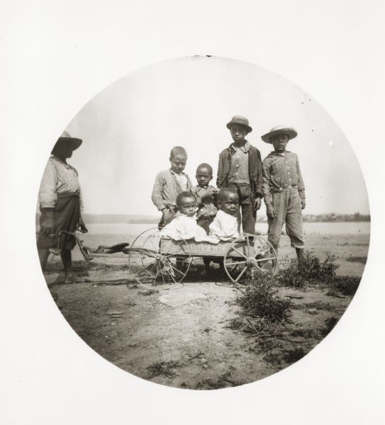 A group of children pose with a small cart.