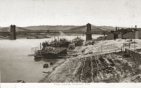 Elevated view over the Ohio River of a boat landing with a bridge in the background.