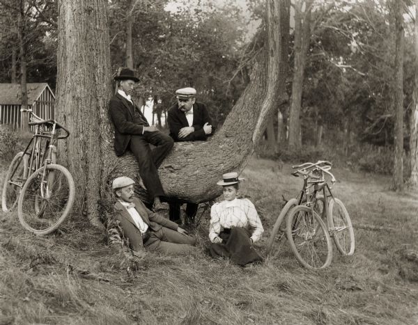 Louis and Henry Harder and Mr. and Mrs. Schildhauer pose by a tree with their bicycles parked nearby. They were probably resting during a bicycle ride on Mendota Drive.