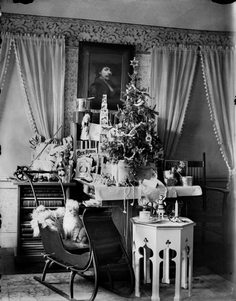 A holiday display in a living room, possibly in the home of Frederick King Conover, which includes a tabletop Christmas tree and a small sleigh.