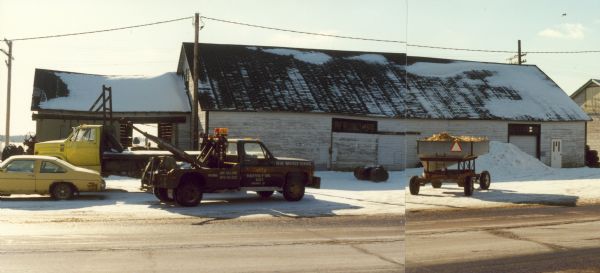 Grain storage building located near the railroad tracks. The wrecker service truck parked near the warehouse bears the slogan, "the happy hooker."
