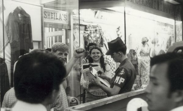 Marine Frank Huff, with upraised fist, being arrested by an MP near the Iwakuni Marine Base in Japan.  Huff, a member of the GI movement of the early 1970s was arrested for distributing anti-war literature.  Judy Currier is the woman with him.