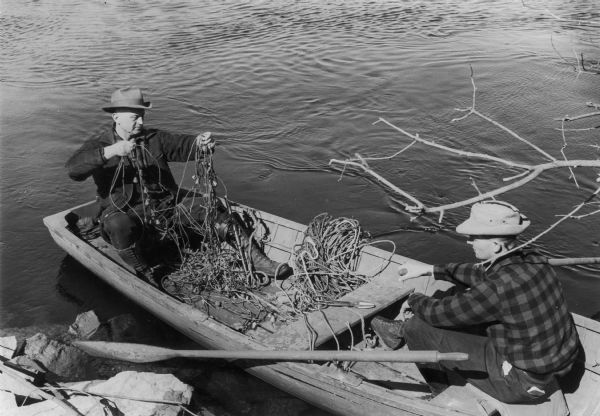 Warden Kramer and his assistant in a boat removing an illegal snag line from the Wolf River.