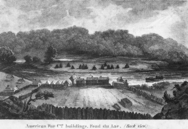 Lithograph view towards river of the American Fur Companies buildings and fenced enclosures, surrounded by hills and trees.