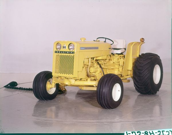 Color photograph of the left side of an International 2444 tractor with a No. 110 Balanced Head Mower attached.