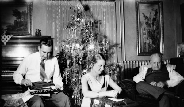 Members of the E.W. Brandel family open gifts in front of a Christmas tree.