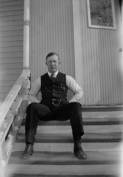 Dr. A.W. "Uncle Bill" (also known in Randolph as "Bill Doc") Jones sits on the porch steps wearing a vest with a watch fob.