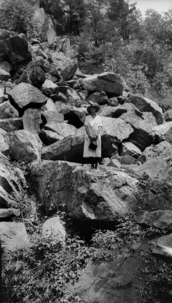 A young woman (probably a member or friend of the Brandel family) posing on a large rock formation surrounded by boulders.
