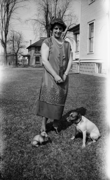 Mrs. Brandel poses outdoors in the yard near the house with Max the family dog and a toy rabbit at her feet.