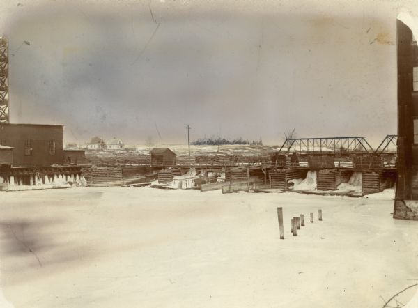 Wolf River Dam with ice and snow. Houses are in the background.