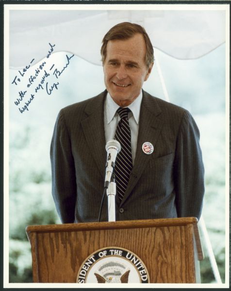 George Herbert Walker Bush stands at a podium during his term as President. The image has an autograph to Lee Sherman Dreyfus that reads "To Lee — With affection and highest regard--George Bush."