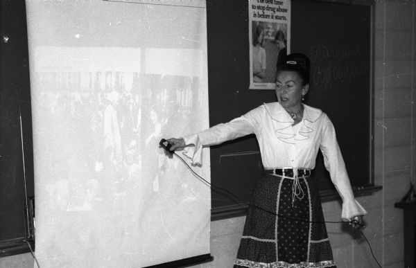 Magda Herzberger points to a photographic image projected onto a screen while giving a lecture about the Holocaust at Monroe High School.