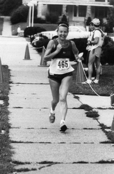 Magda Herzberger running on a sidewalk in a Dubuque marathon.