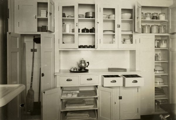 Interior view of a University of Wisconsin Home Economics Department practice kitchen demonstrating orderly shelf usage.