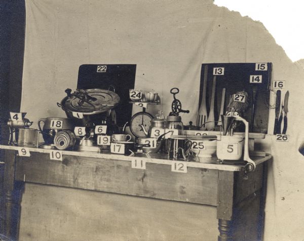 Table at a Farmers' Institute event with display of numbered kitchen tools and machinery.