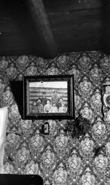 Photograph hanging on the wall of the family cabin of John F. Deitz. The glass of the picture was broken by a bullet piercing the walls between the logs in the battle which had occurred a few weeks earlier, between Deitz and the Sheriff's deputies.