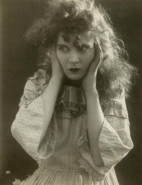 Publicity still from the silent film <i>The Birth of a Nation</i> of Mae Marsh with her hands held to her face.