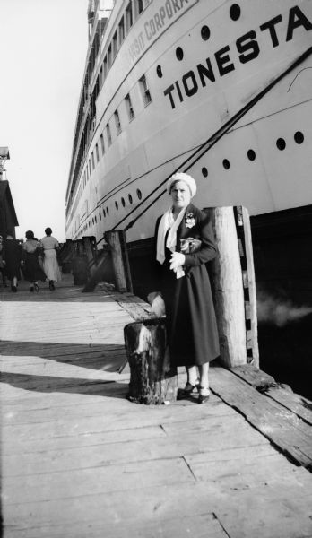 Mrs. Brandel poses on a dock in front of the ship the <i>Tionesta</i>.