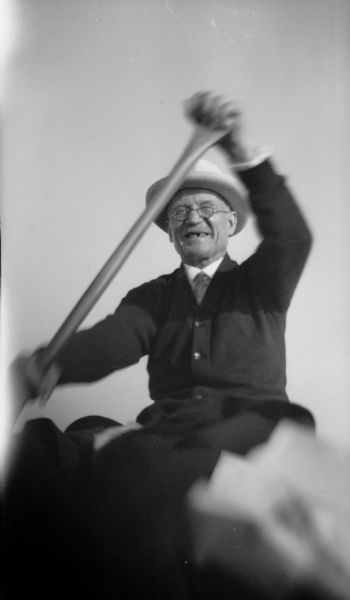 "Gramps" (E.W.) Brandel wearing a hat and eyeglasses, paddling with a big smile on his face.
